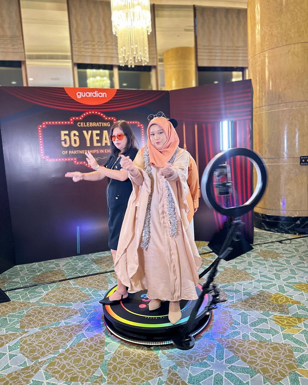 People standing on 360 spin pod while camera rotates capturing immersive event video